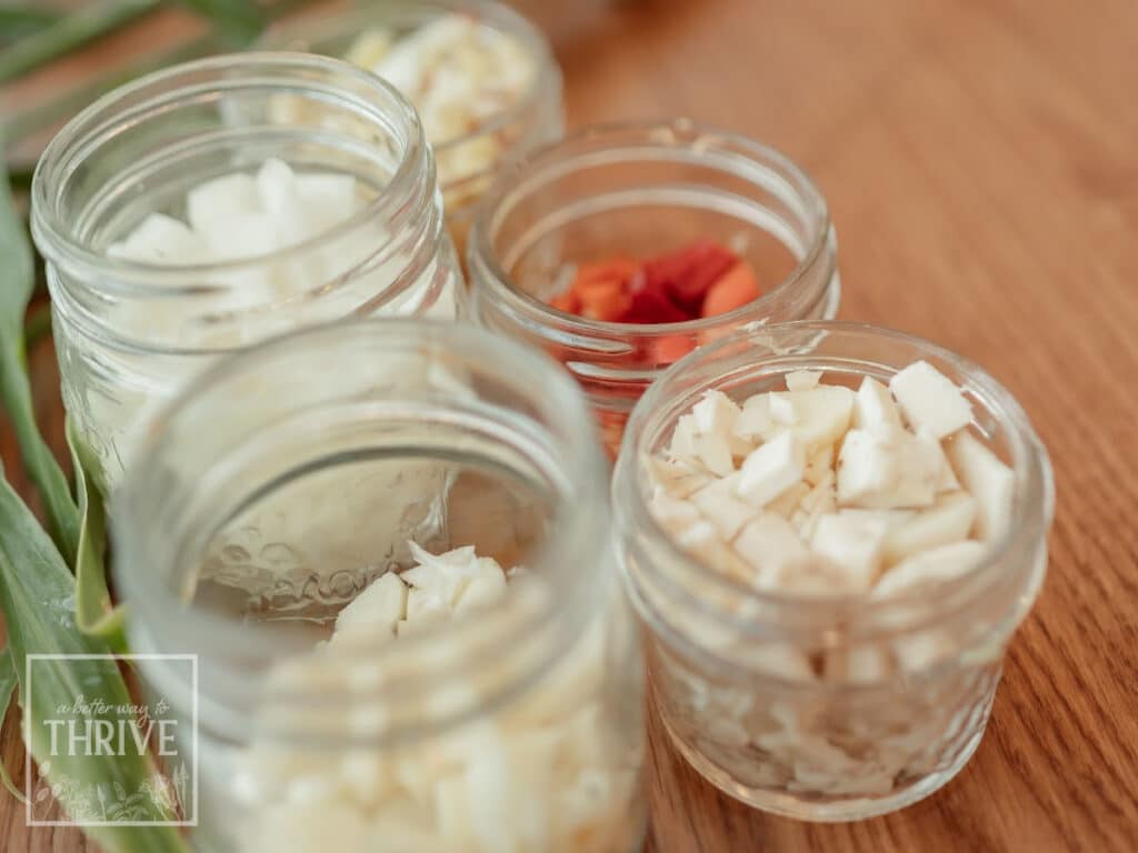 Chopping ingredients in jars for a homemade fire cider recipe