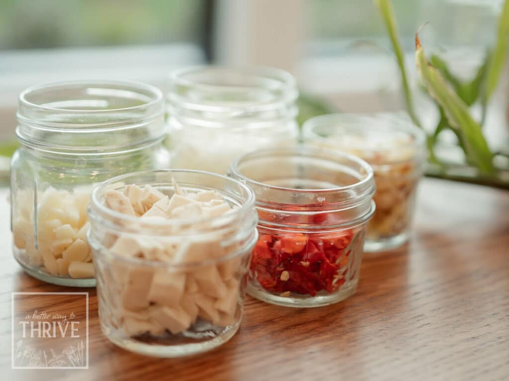Jars of fire cider ingredients_ garlic, horseradish, onion, hot pepper, and ginger