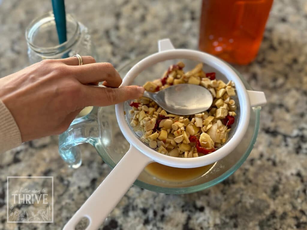 Straining a homemade fire cider recipe through a sieve